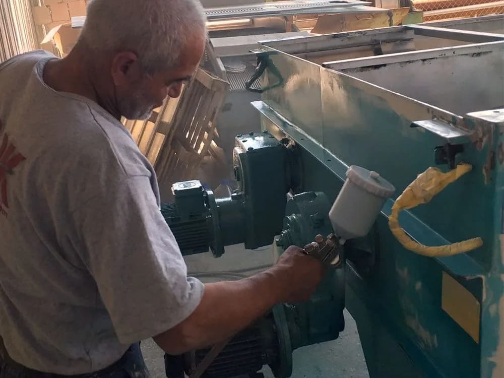 Mustafa Usta makine gövdesini boya tabancasıyla boyarken